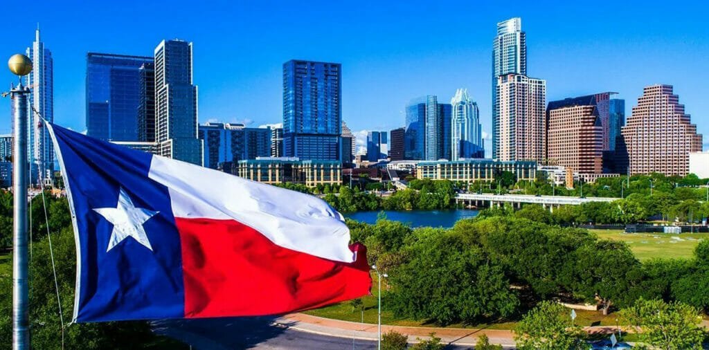 A Austin flag flies in front of a city skyline.