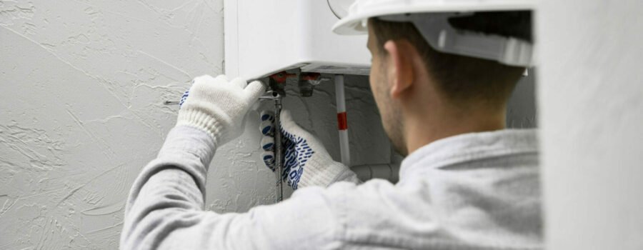 A man in a hard hat is working on a water heater, hired by Patriot Appliance & Air Conditioning Repair Service in Austin.